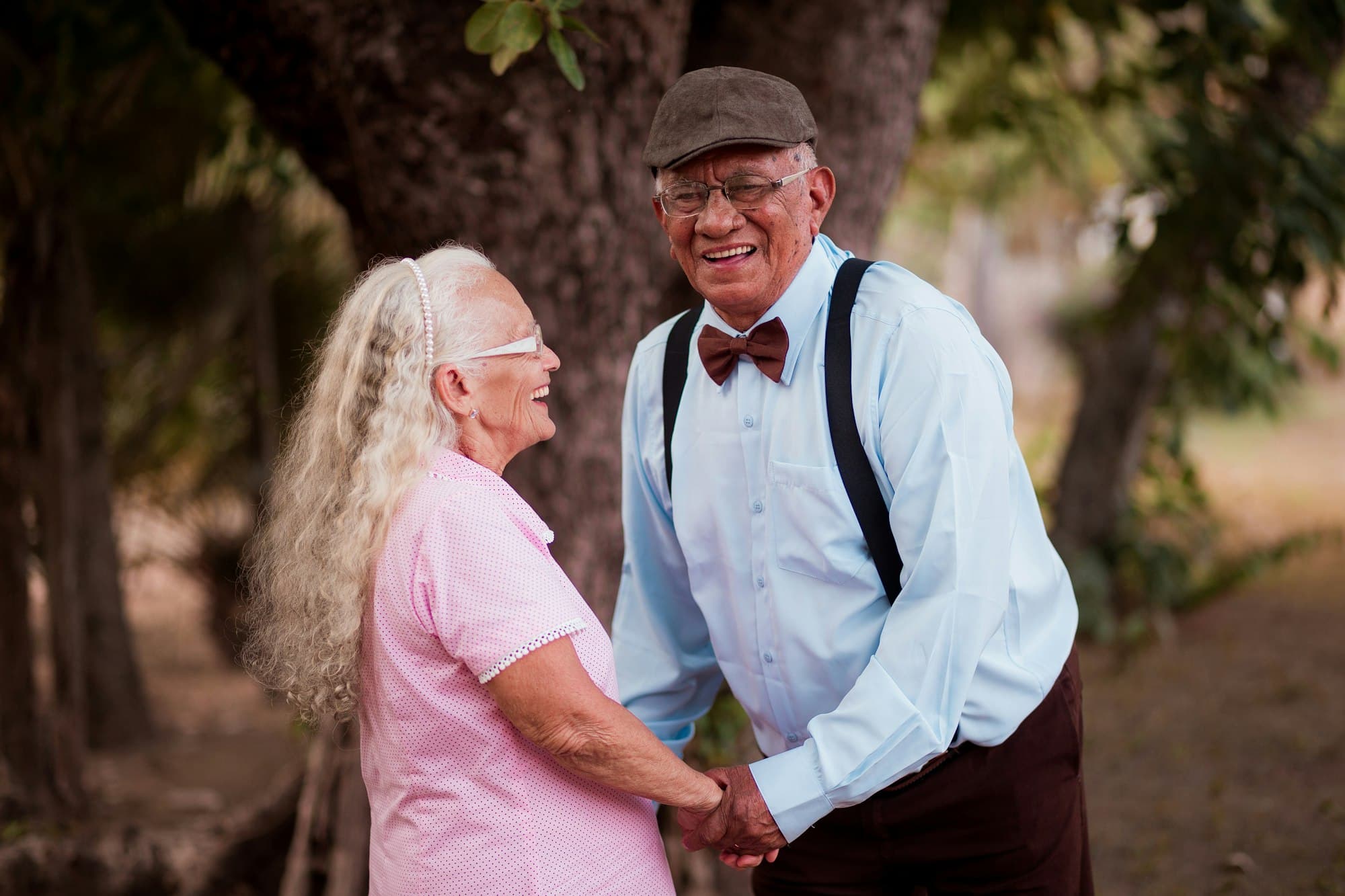 Casal de idosos de mãos dadas, sorrindo ao ar livre